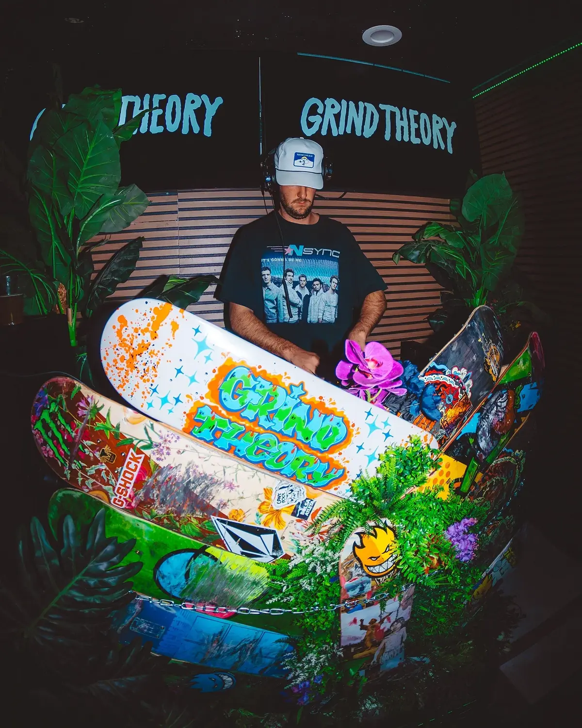 Sean with a stack of hand-painted Grind Theory decks in front of a mural